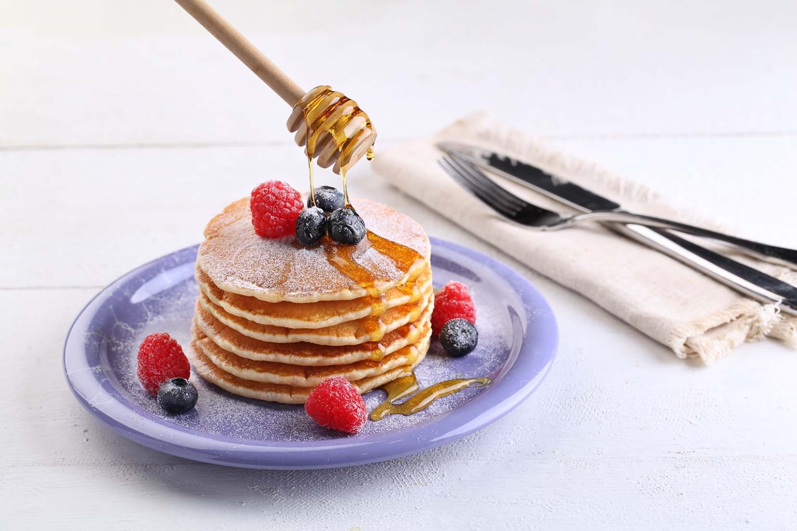 Pancake with honey, raspberries and blueberries on top