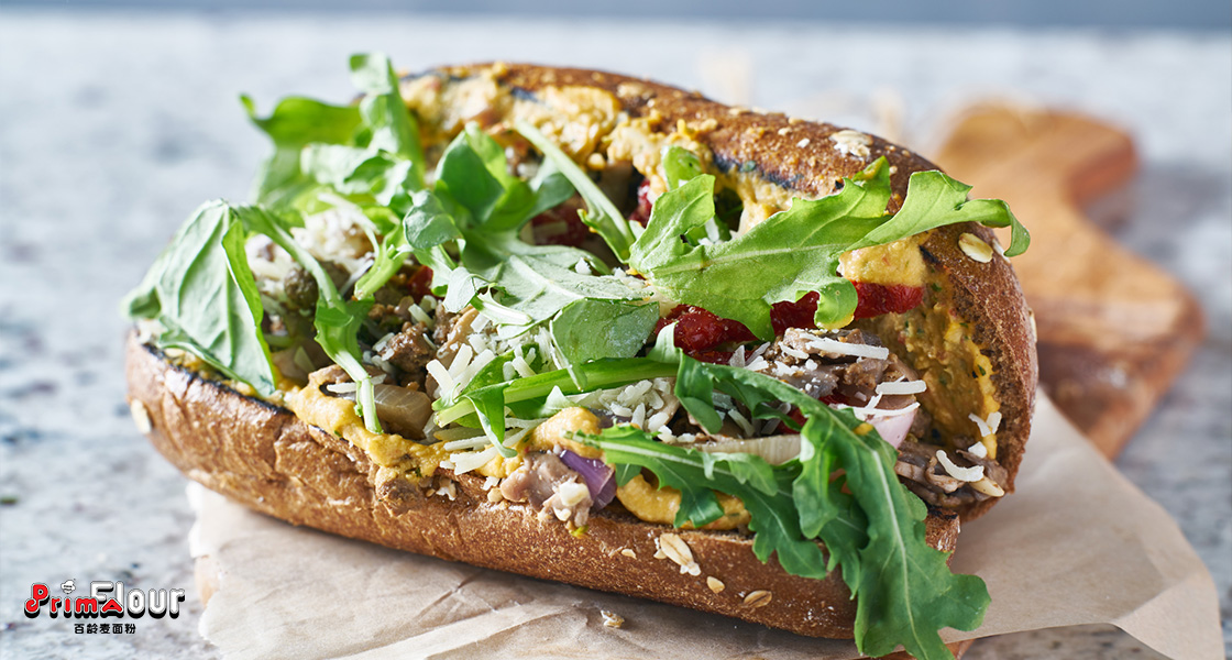 Whole wheat flour sandwich with roasted veggies, hummus, and arugula